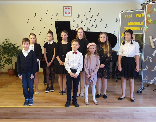 grupa dzieci stojących na tle fortepianu