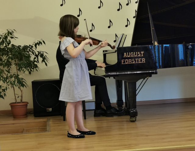 dziewczynka gra na skrzypcach, mężczyzna akompaniuje na fortepianie